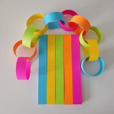 a bunch of different colored paper on top of each other with ribbons attached to them