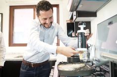 a man standing in front of a frying pan on top of a kitchen stove