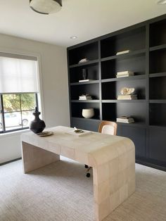 a room with a table, chairs and bookshelves in it's center