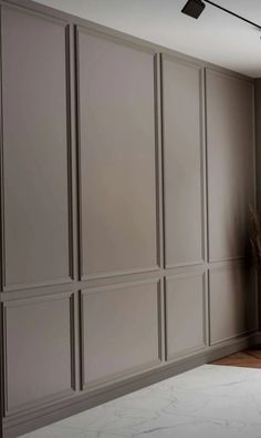 an empty room with gray paneling and white marble counter top, in front of a large window