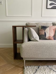 a couch with pillows on it in front of a painting and wooden flooring area