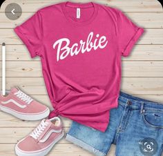 a pink shirt with the word barbie written on it next to some shorts and sneakers