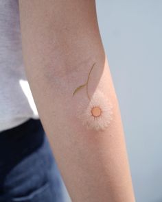 a woman's arm with a small white flower on the back of her arm