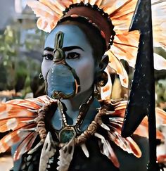 a woman with an elaborate headdress and face paint holding a knife in her hand