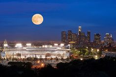 a full moon is seen over a city at night