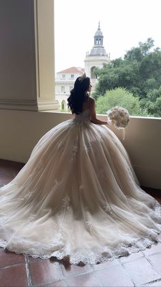 a woman in a wedding dress looking out the window