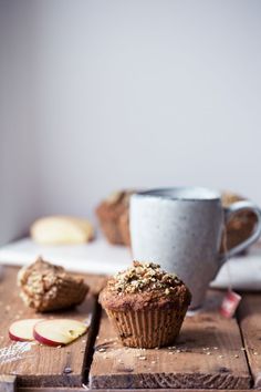 some muffins are sitting on a table next to an apple and coffee cup