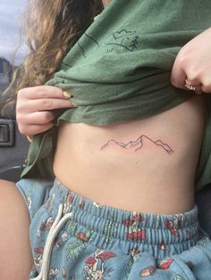 a woman with a mountain tattoo on her stomach is holding onto the side of her waist