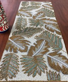 a table with a vase on top of it next to a rug that looks like leaves