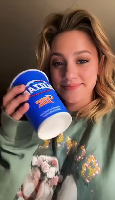 a woman is holding a cup and smiling