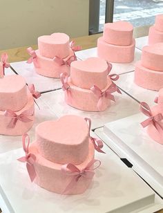 many pink cakes with bows are on display