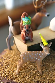 small deer figurines on top of a cake with other animals in the background