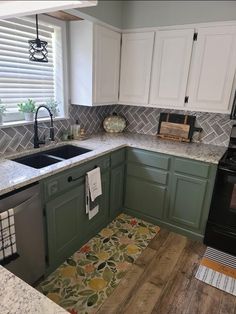 a kitchen with green cabinets and white cupboards, wood flooring and marble counter tops