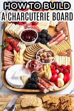 a wooden platter filled with cheese, crackers and fruit