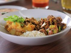 a white bowl filled with meat, rice and vegetables on top of a wooden table