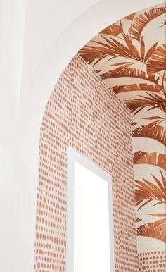 an arched window in the corner of a room with wallpaper and palm leaves on it