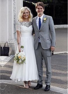 a man and woman standing next to each other in front of a white building wearing formal attire