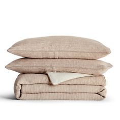 three pillows stacked on top of each other with one white pillow and the other light brown