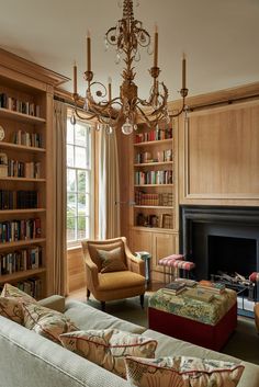 a living room filled with lots of furniture and a fire place under a chandelier