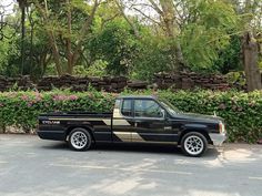 a black pickup truck parked in front of some bushes