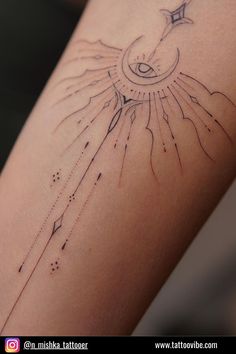 a woman's arm with an arrow and sun tattoo on the back of it