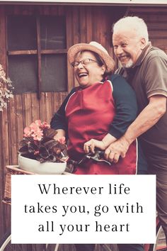 an older couple standing next to each other with a sign that says wherever life takes you, go with all your heart