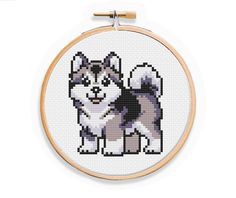 a cross stitch dog with black and white spots on it's face is shown