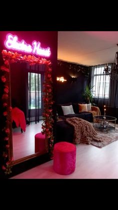 a living room filled with furniture and a pink neon sign on the wall above it