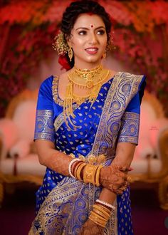 a woman wearing a blue and gold bridal outfit with her hands on her chest