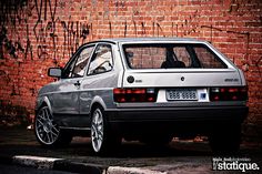 a silver car parked in front of a brick wall