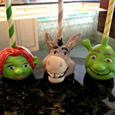 three toy heads sitting on top of a counter next to two candy canes in the shape of animals