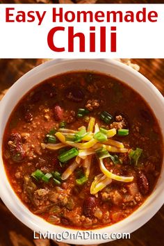 a white bowl filled with chili and cheese on top of a wooden table next to crackers