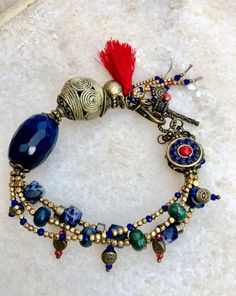 a close up of a bracelet on a white surface with beads and charms around it