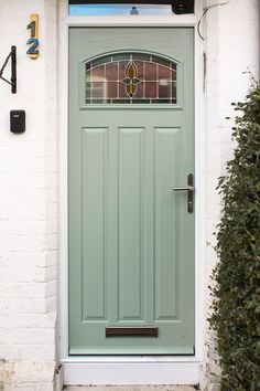 a green front door on a white brick house with stained glass window and sidelight