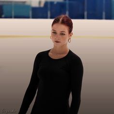 a woman standing in front of an ice rink with her hands on her hips and looking at the camera