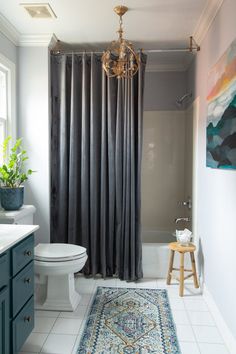 a bathroom with blue cabinets and a rug on the floor in front of the shower