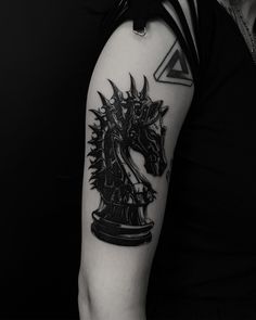 a black and white photo of a chess piece tattoo on the left upper half of the arm