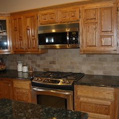 a kitchen with granite counter tops and wooden cabinets, along with stainless steel oven hoods