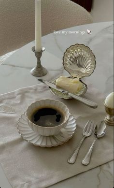 there is a cup of coffee on the table next to a plate with cake in it