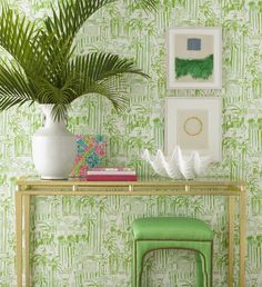 a table with two stools next to a plant and some pictures on the wall