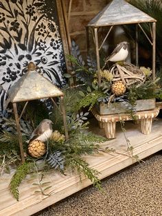 three bird figurines sitting on top of a mantle with pine cones and greenery