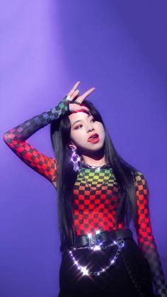 a woman with long black hair wearing a colorful dress and holding her hands up in the air