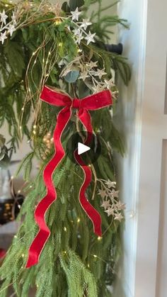 a christmas wreath with red ribbon hanging from it's side and snowflakes on the top