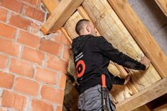 a man is working on the roof of a house with wood framing around his body