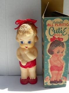 an old plastic doll next to a box