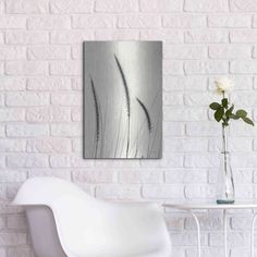 a white chair in front of a brick wall with flowers on the table next to it