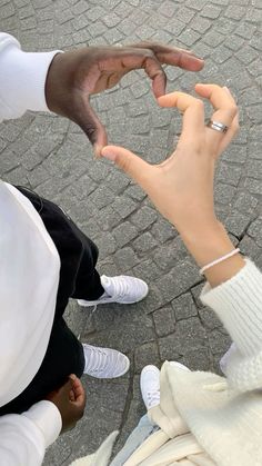 two people reaching out their hands to touch each other's fingers while sitting on the ground