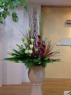 two vases filled with flowers sitting on top of a wooden table next to a lamp