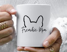 a woman holding a white coffee mug with the word corgi mom on it