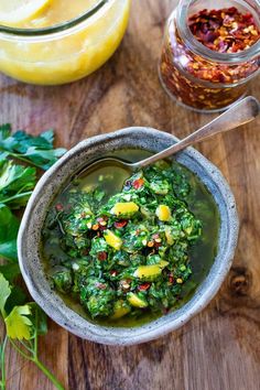 a bowl filled with green soup next to some lemons and other ingredients on a wooden table